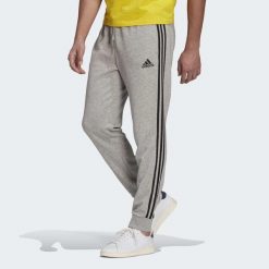 Spodnie męskie adidas ESSENTIALS 3-STRIPES. Czarne spodnie materiałowe Adidas, m, bez wzorów, z polaru. Za 163.99 zł.