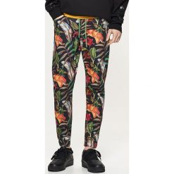 Materiałowe joggery z kwiatowym printem all over - Czarny. Spodnie materiałowe marki Cropp. W wyprzedaży za 49.99 zł.