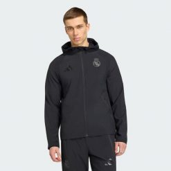 Wiatrówka Real Madryt Travel z suwakiem na całej długości. Czarne bluzy Adidas, bez wzorów, z kapturem. Za 399.00 zł.