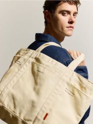 Materiałowa torba na ramię - złamana biel. Torby na ramię Reserved, bez wzorów, z materiału, na ramię, małe, bez dodatków. Za 69.99 zł.