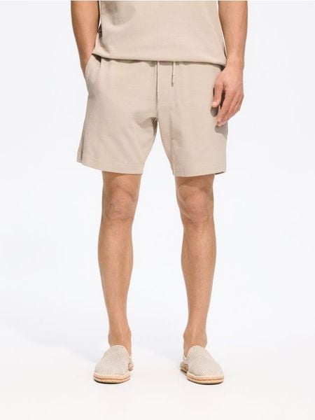 Dresowe szorty regular fit - beżowy. Brązowe krótkie spodenki sportowe Reserved, l, bez wzorów, z bawełny. Za 89.99 zł.