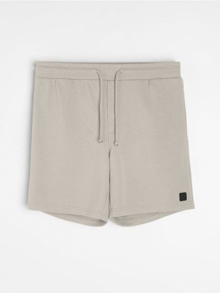 Szorty dresowe z wiązaniem - kremowy. Białe krótkie spodenki sportowe Sinsay, l, bez wzorów, z dresówki. Za 39.99 zł.