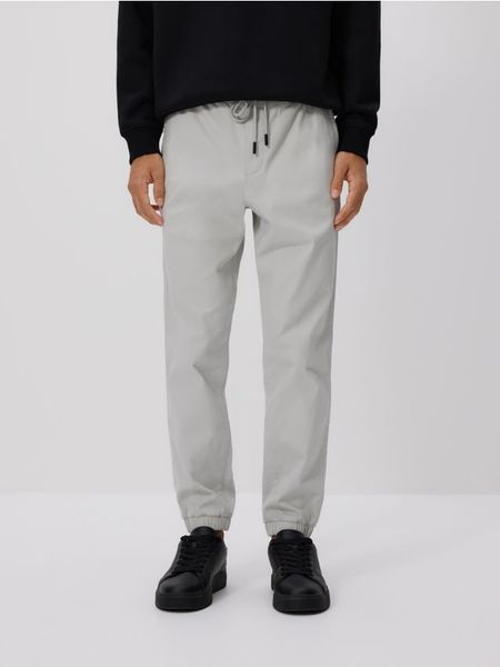 Bawełniane spodnie jogger - jasnoszary. Szare joggery i bojówki Reserved, l, bez wzorów, z bawełny. W wyprzedaży za 55.99 zł.