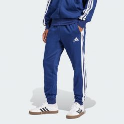 Spodnie Essentials 3-Stripes Fleece. Białe spodnie materiałowe Adidas, na co dzień, bez wzorów, sportowe. Za 214.25 zł.
