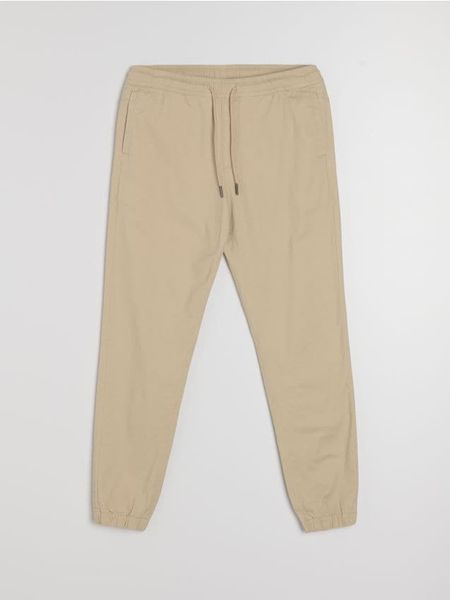 Bawełniane spodnie jogger - beżowy. Brązowe joggery i bojówki Sinsay, bez wzorów, z bawełny. Za 49.99 zł.