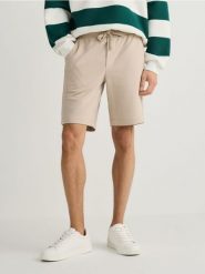 Dresowe szorty regular fit - beżowy. Brązowe krótkie spodenki sportowe Reserved, l, bez wzorów, z bawełny. Za 79.99 zł.