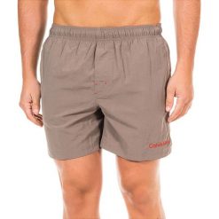Szorty kąpielowe w kolorze szarobrązowym. Klapki marki CALVIN KLEIN. W wyprzedaży za 173.95 zł.